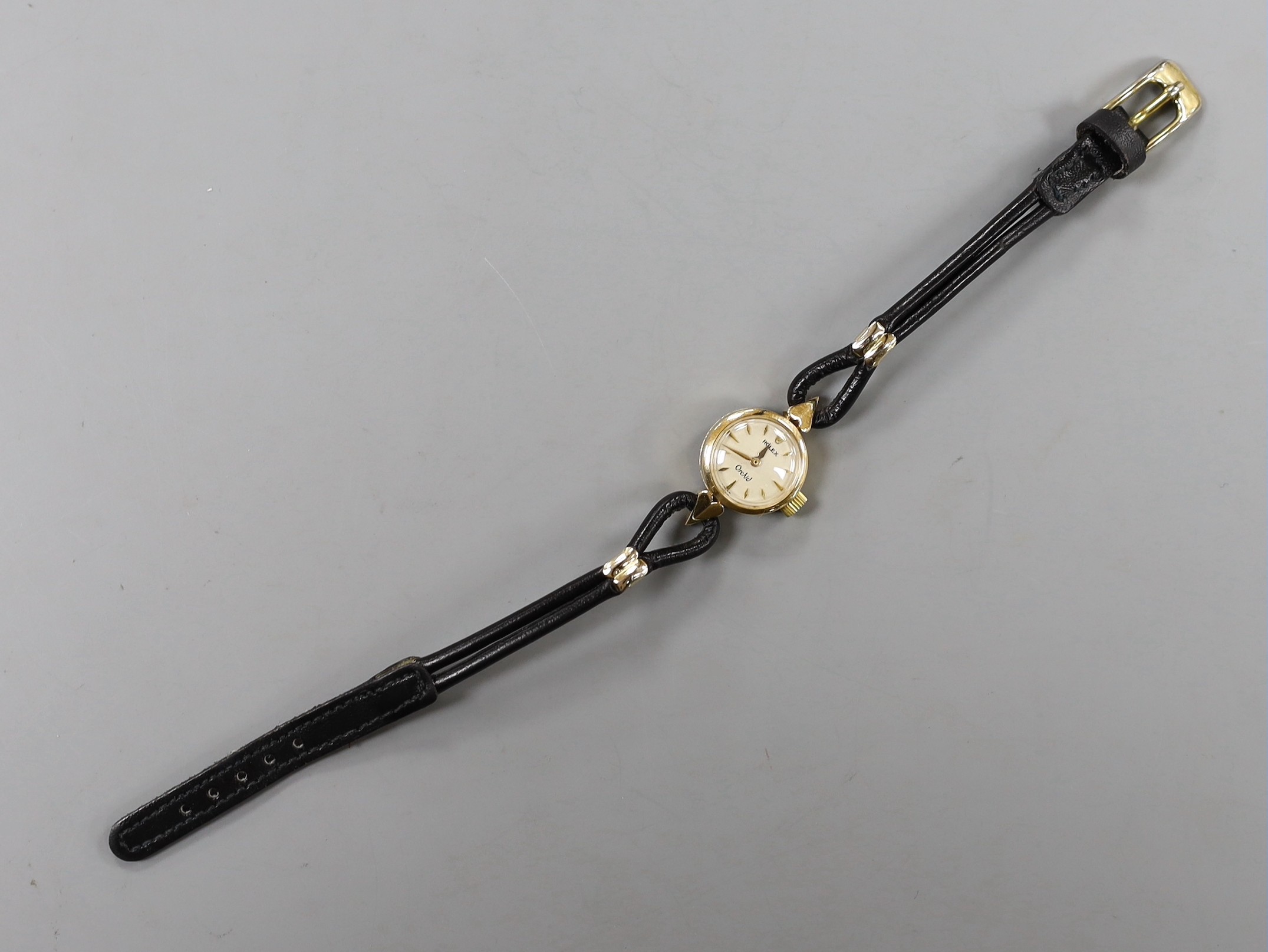 A lady's mid 20th century 750 yellow metal Rolex Orchid manual wind wrist watch, with engraved inscription, on associated leather strap.